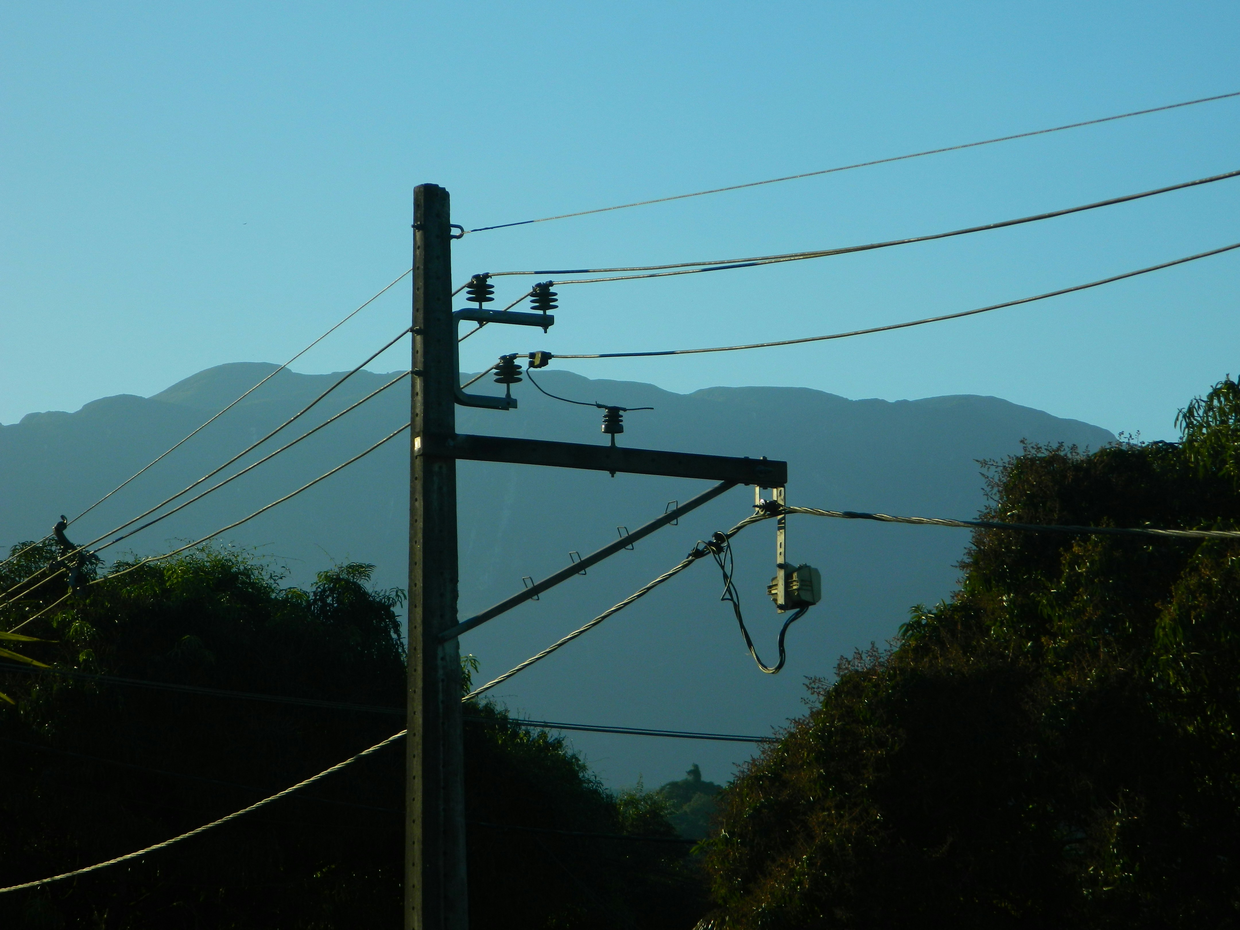 A telephone pole and power lines with mountains in the background
