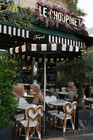 A teddy bear sitting at a table in front of a restaurant
