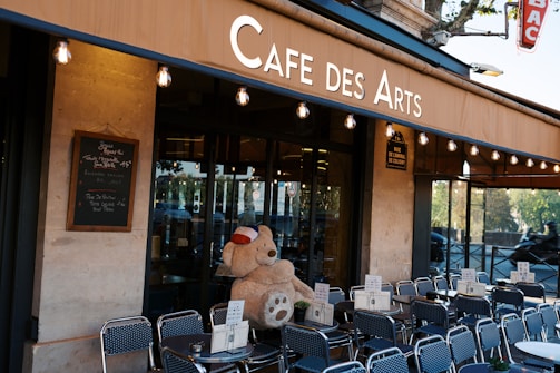 A teddy bear sitting in the window of a cafe