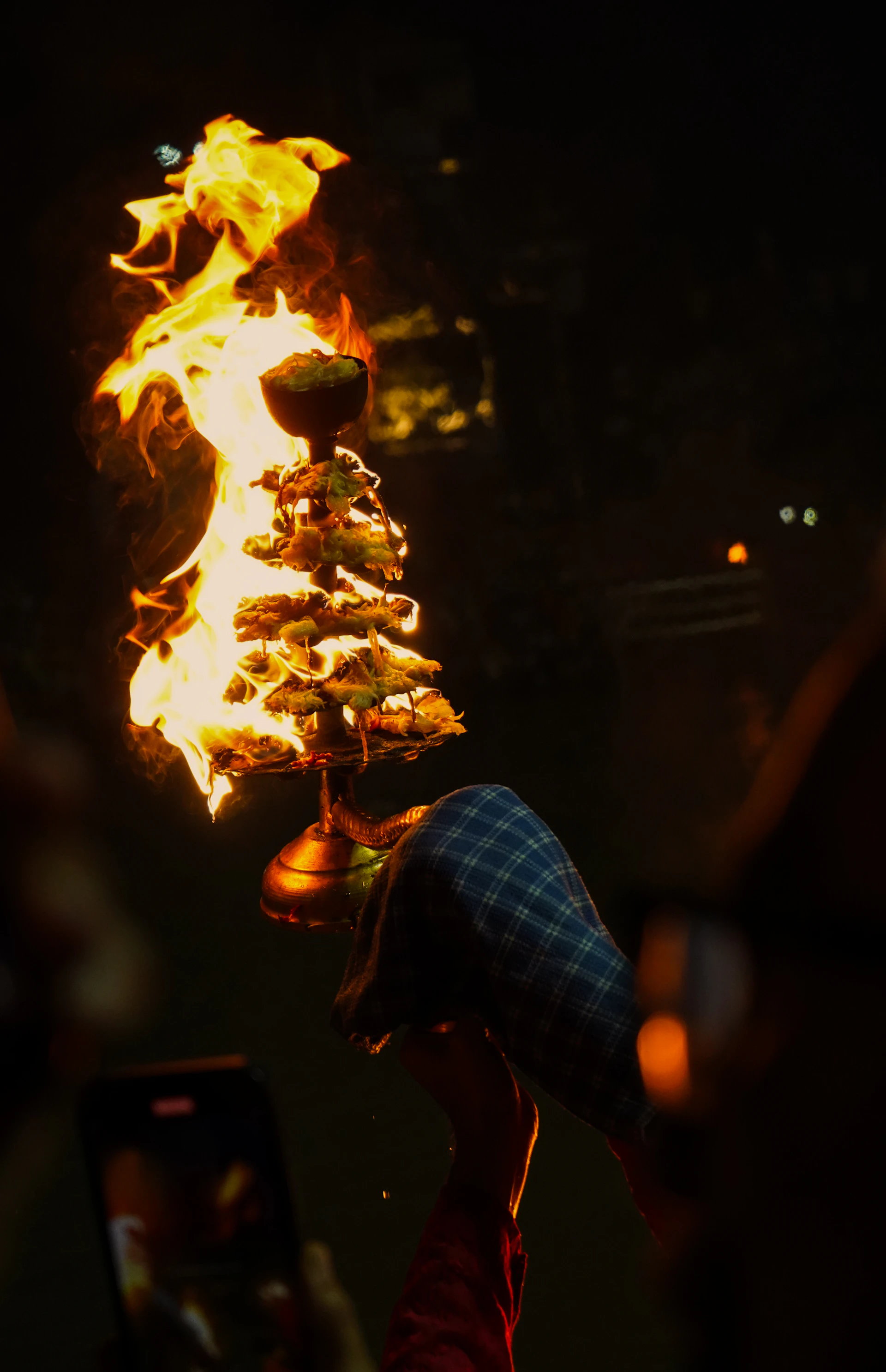 A person holding a cell phone in front of a fire