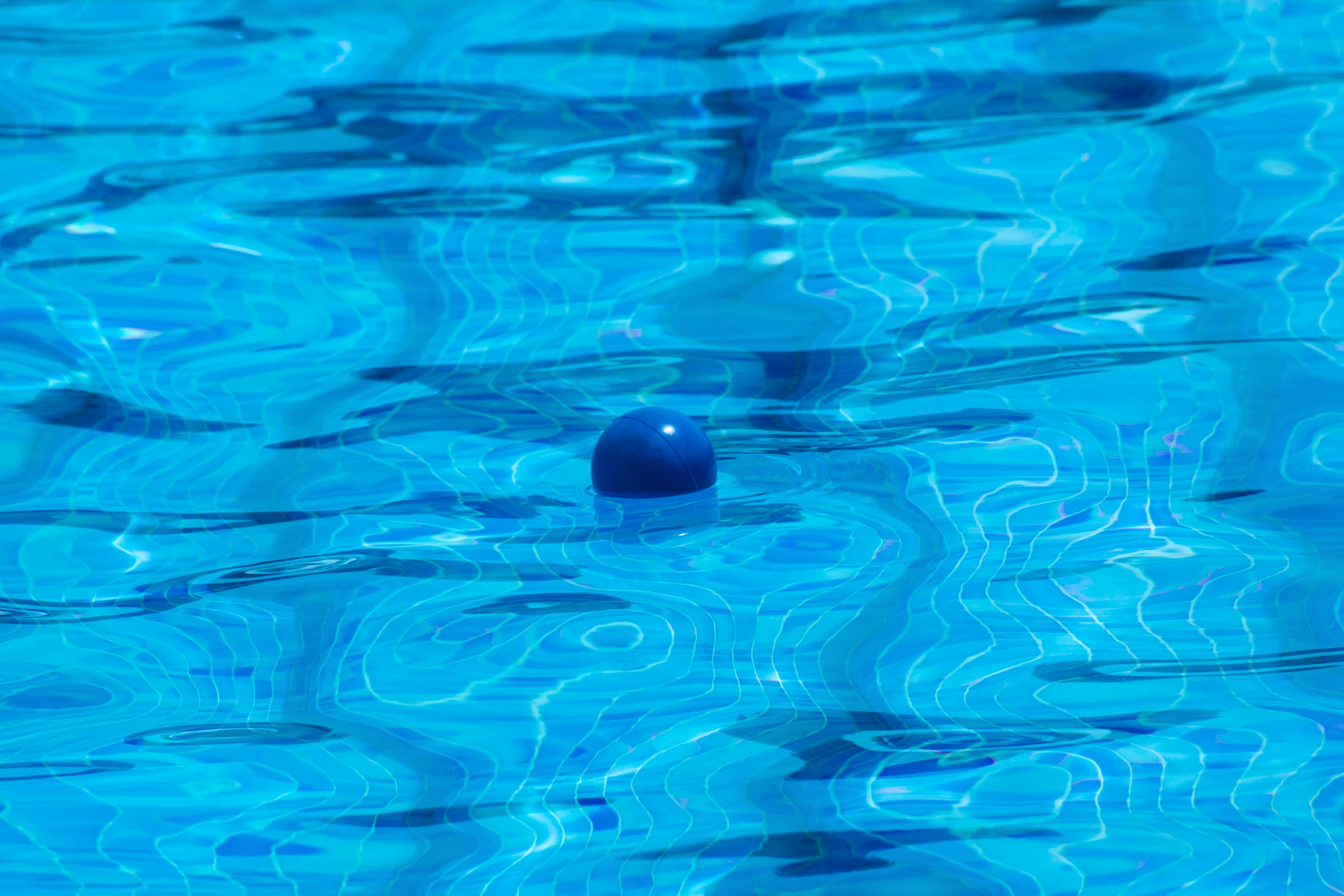 A pool with blue water and a ball in the middle