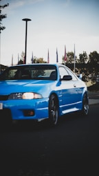 A blue car driving down a street next to flags