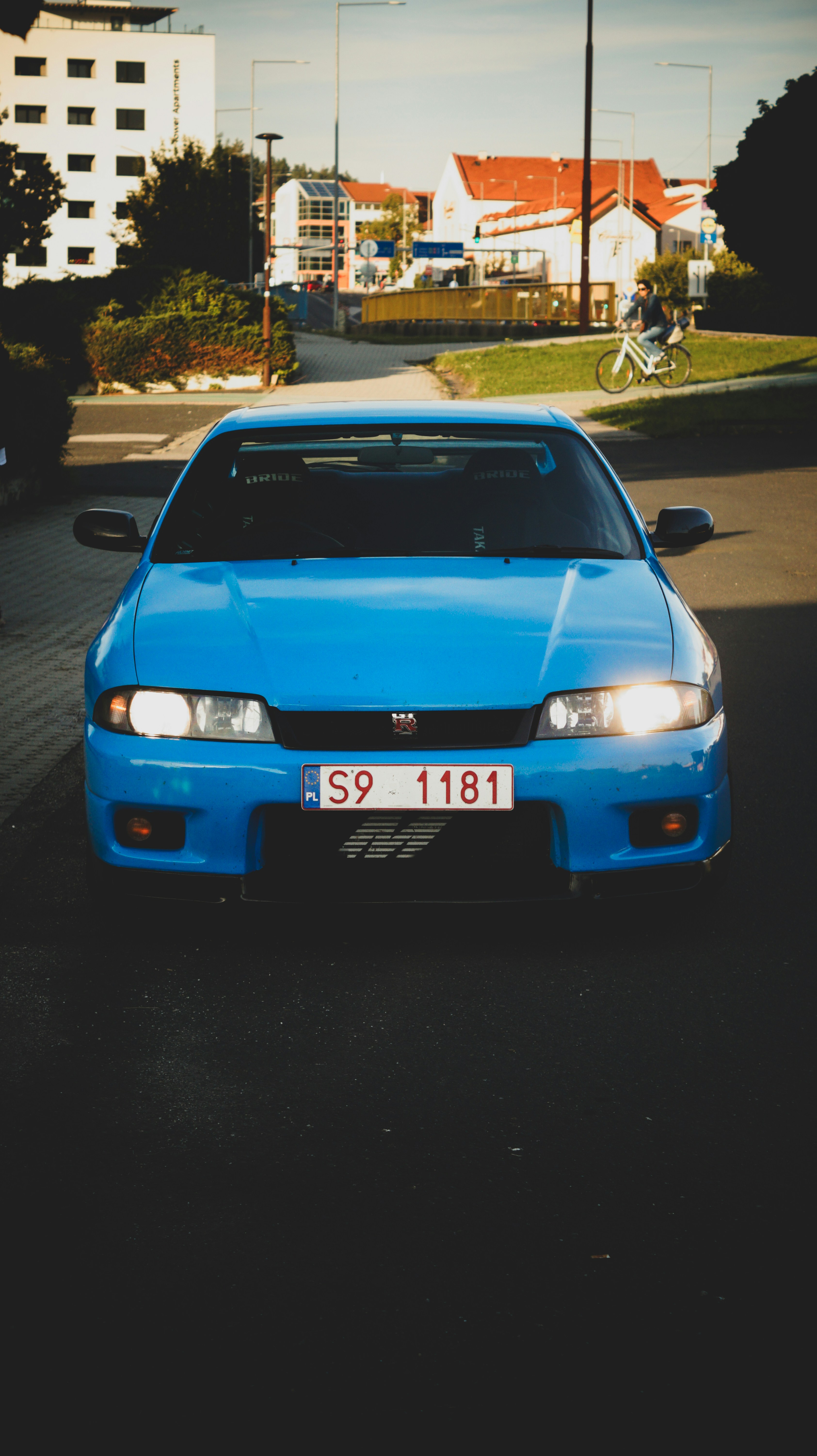 A blue car driving down a street next to tall buildings photo – Free ...