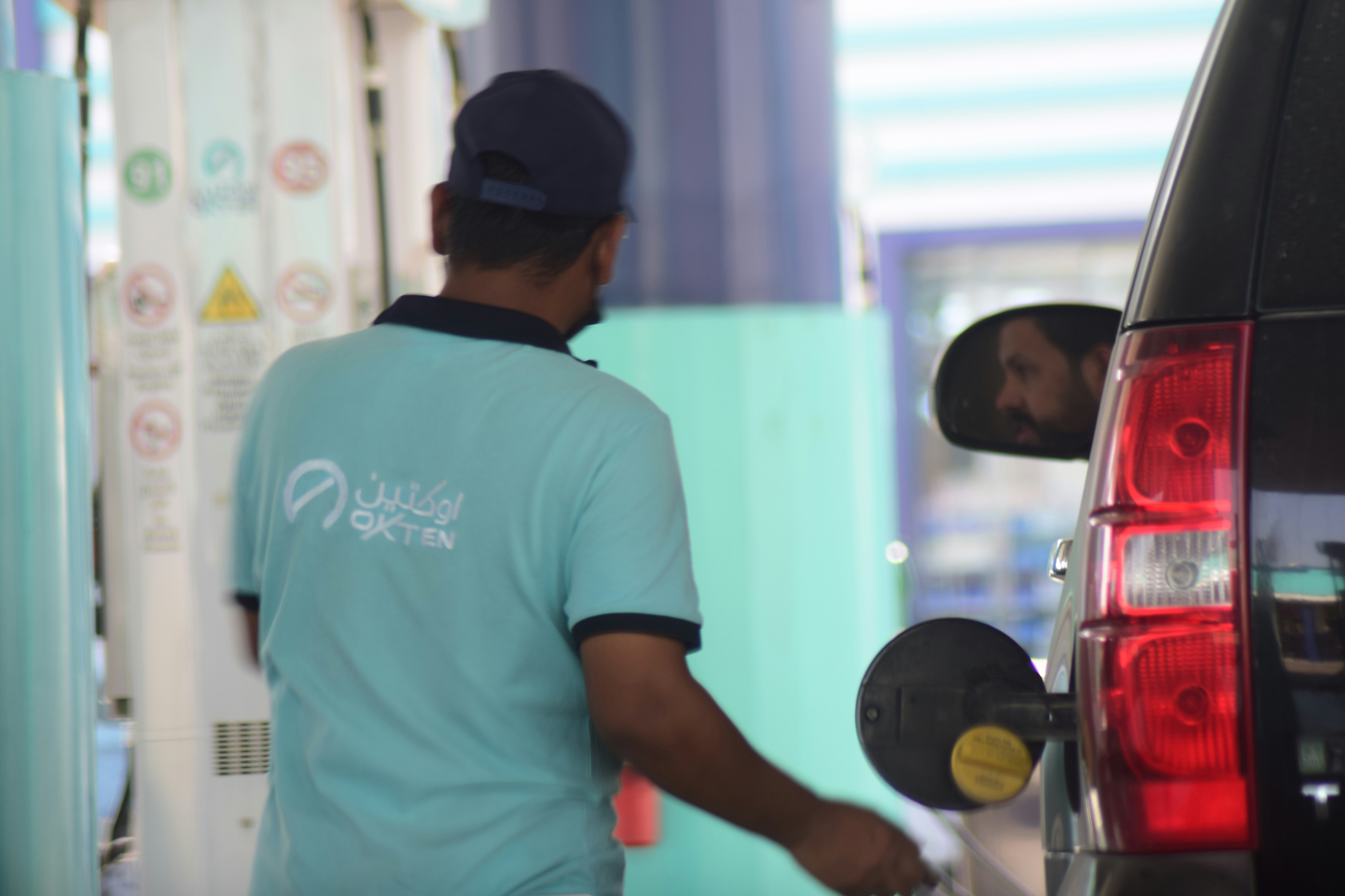A man filling up his car with gas at a gas station