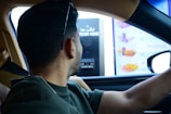 A man driving a car in front of a vending machine