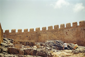 Two people are sitting on a rock in front of a castle