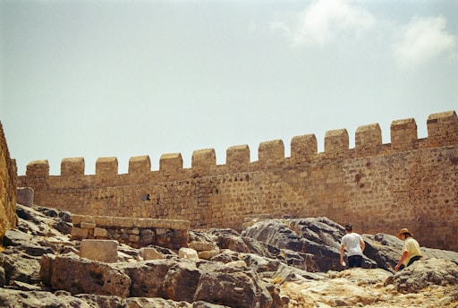 Two people are sitting on a rock in front of a castle