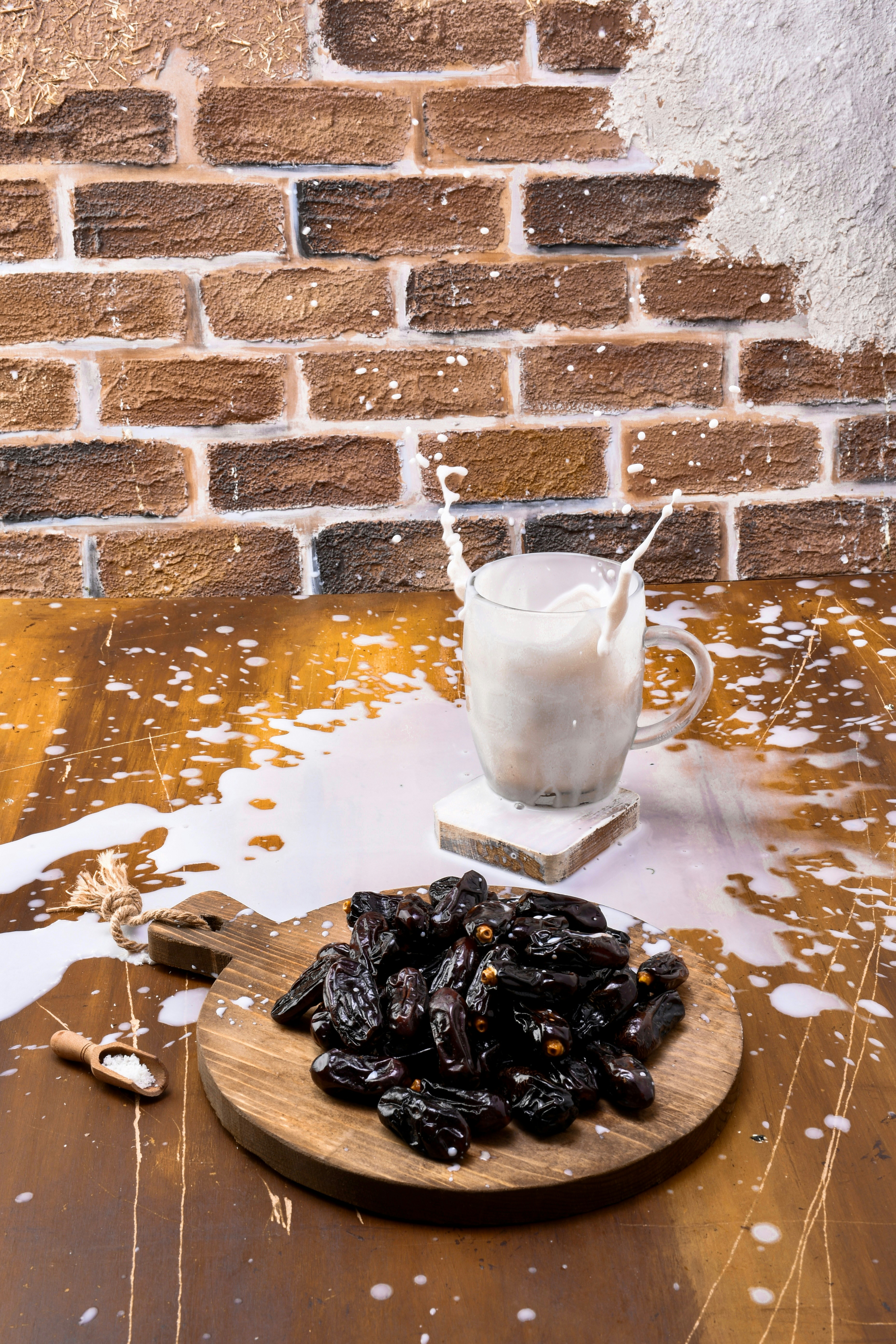 A wooden table topped with raisins next to a glass of milk