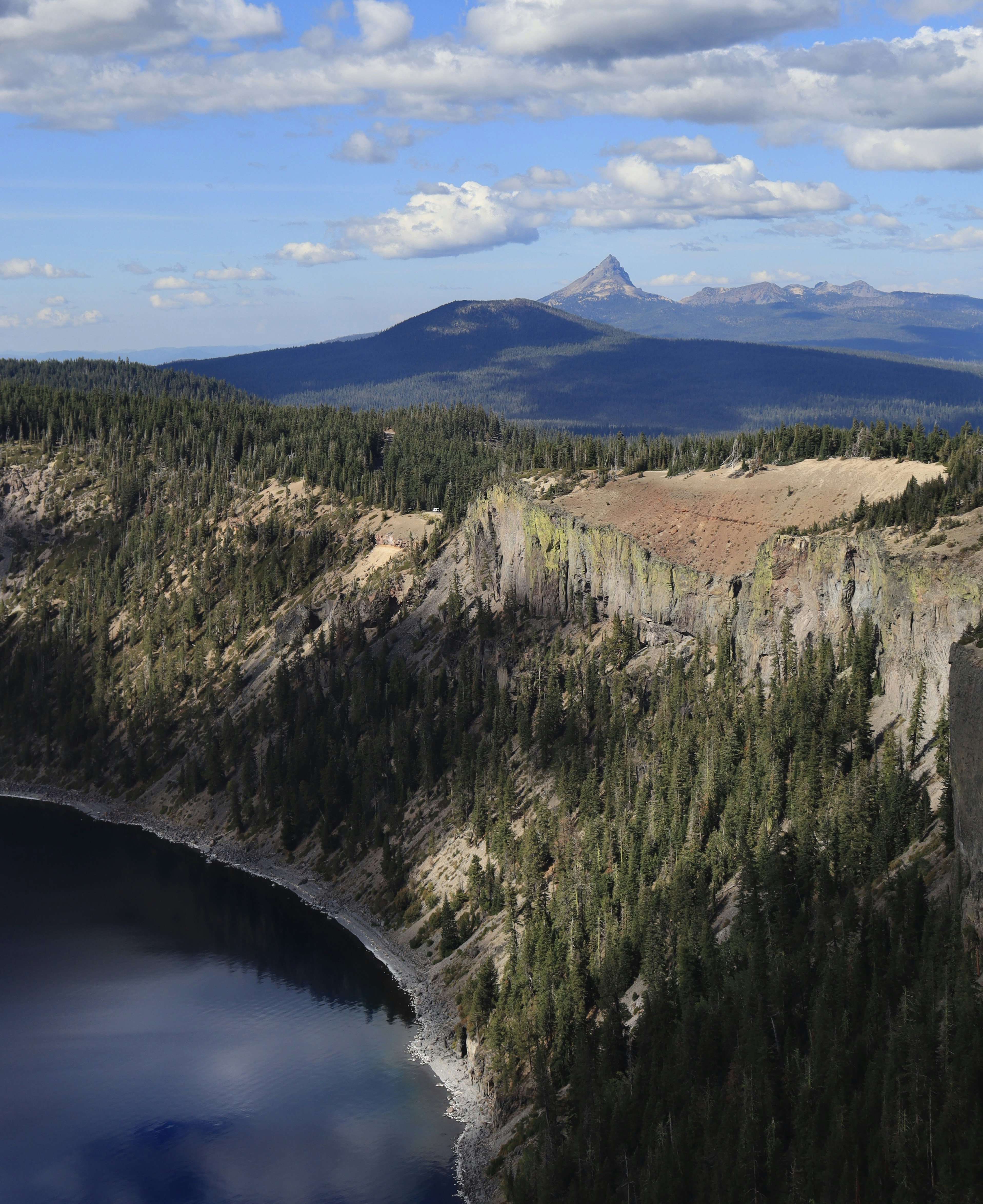A lake surrounded by trees and mountains under a cloudy sky