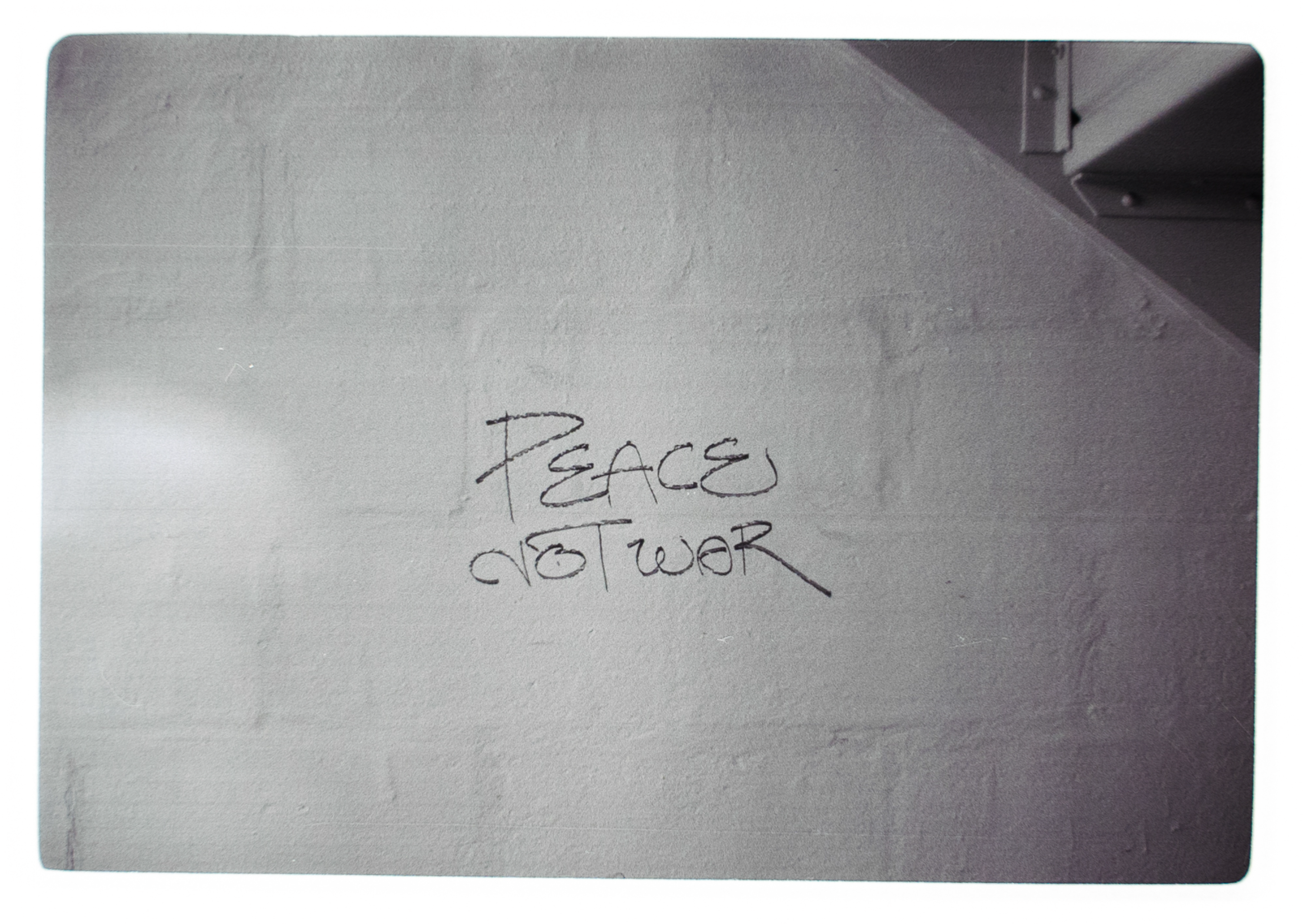 Graffiti on a white brick wall says peace not war