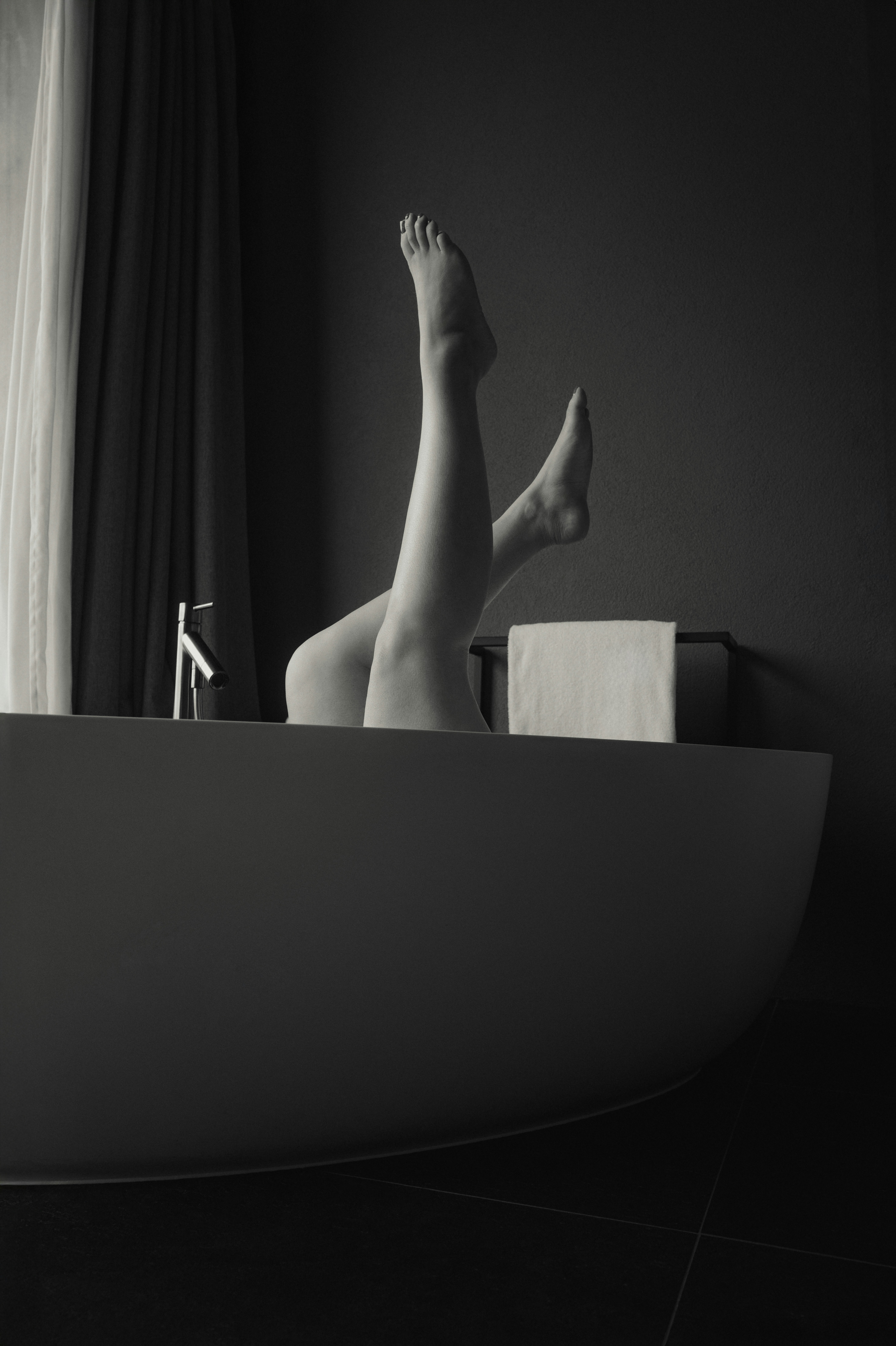 A black and white photo of a woman's legs in a bathtub