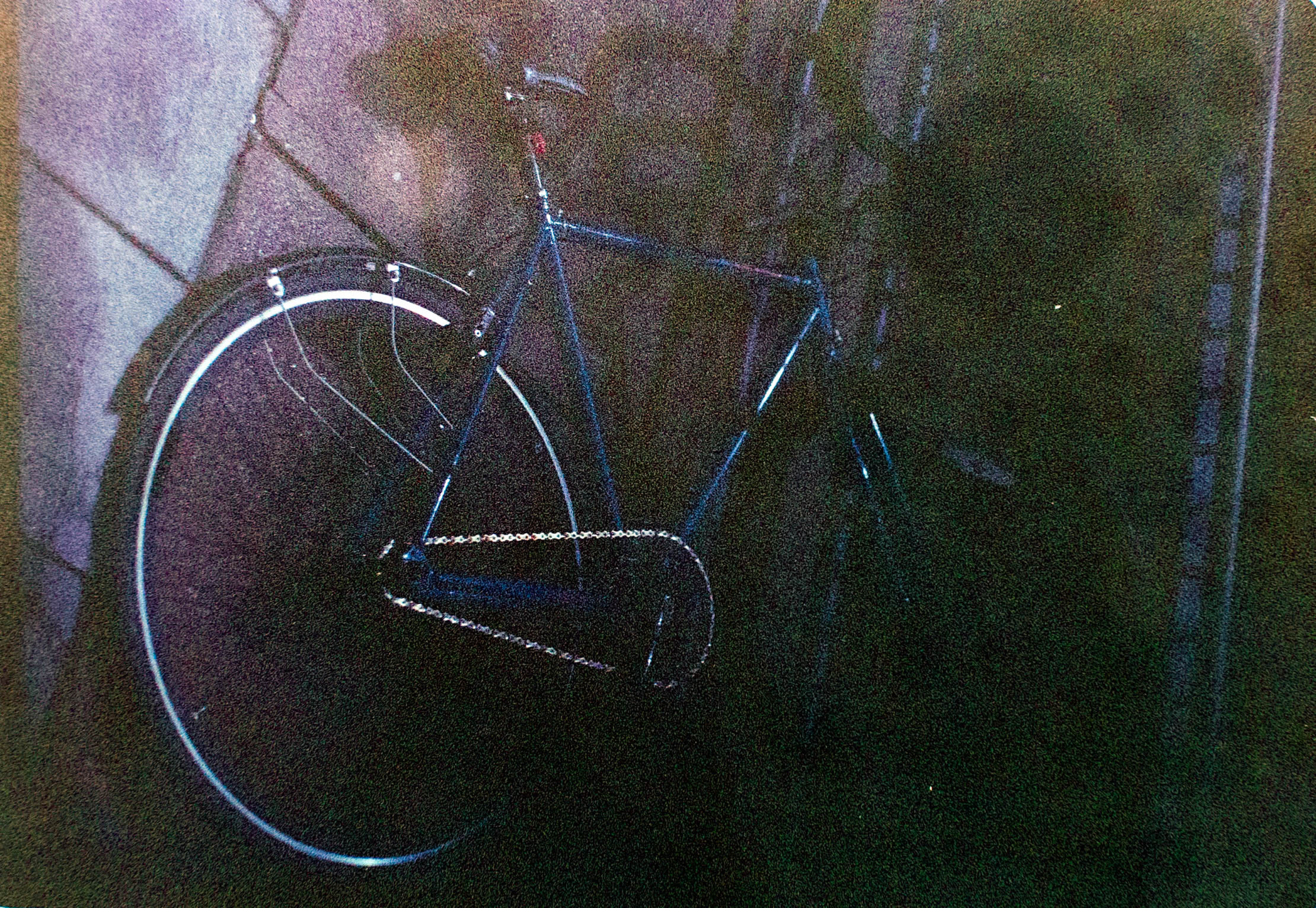 Uma bicicleta azul-escura encosta em uma parede texturizada.