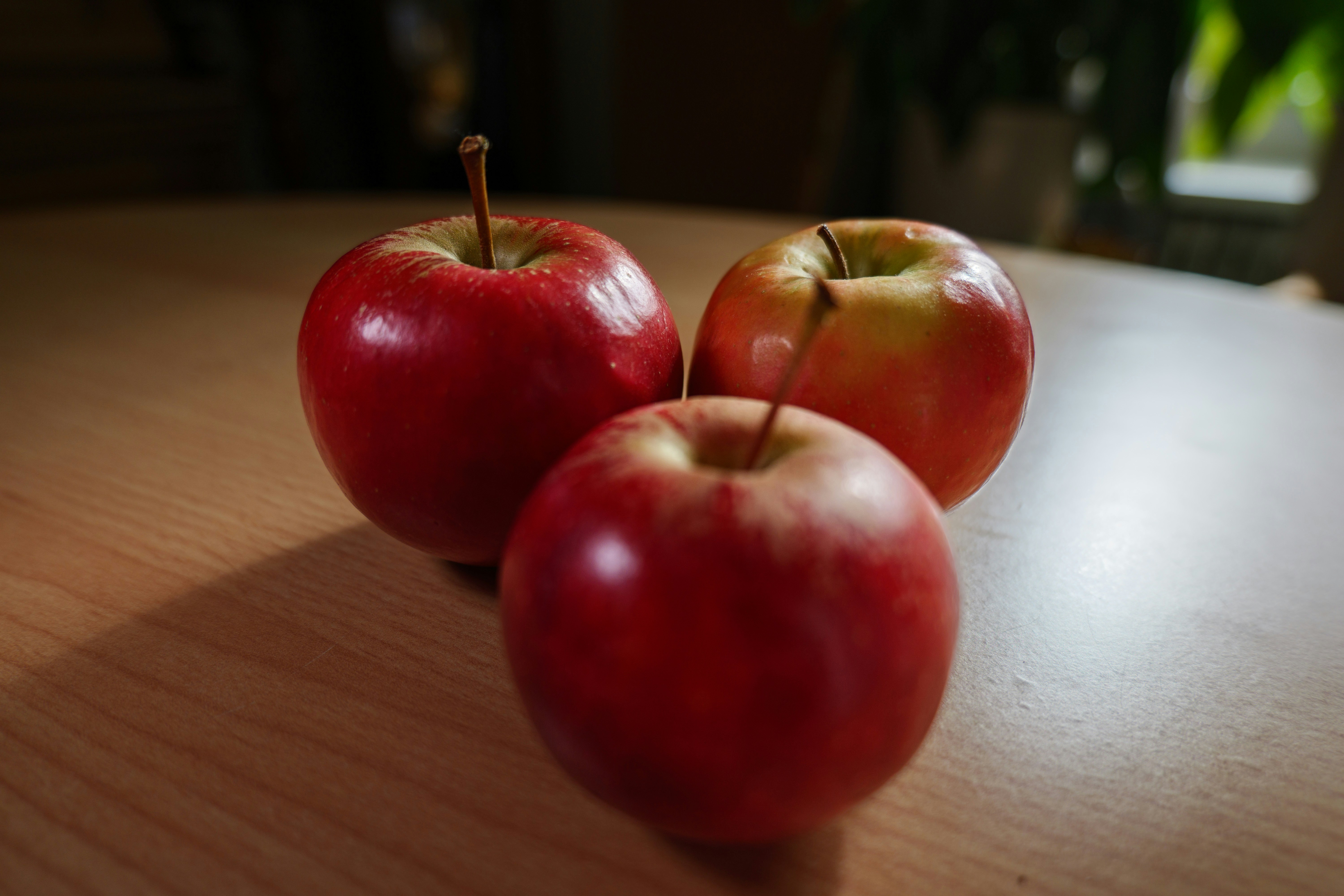 Two red apples sitting on top of a wooden table