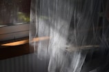 A cat sitting on a window sill in front of a curtain
