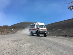 A white bus driving down a dirt road