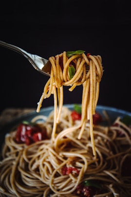 A fork full of spaghetti being lifted from a bowl