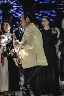A group of people standing around a man playing a saxophone