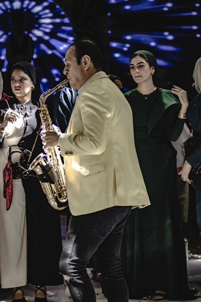 A group of people standing around a man playing a saxophone