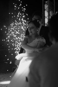 A bride and groom standing in front of a firework display
