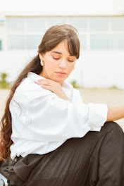A woman sitting on the ground with her hand on her shoulder