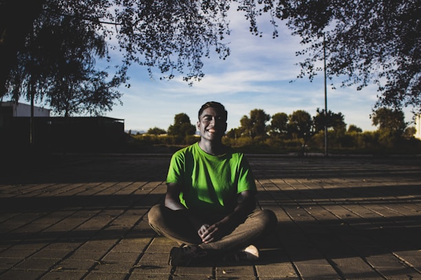 A man in a green shirt sitting on a wooden floor