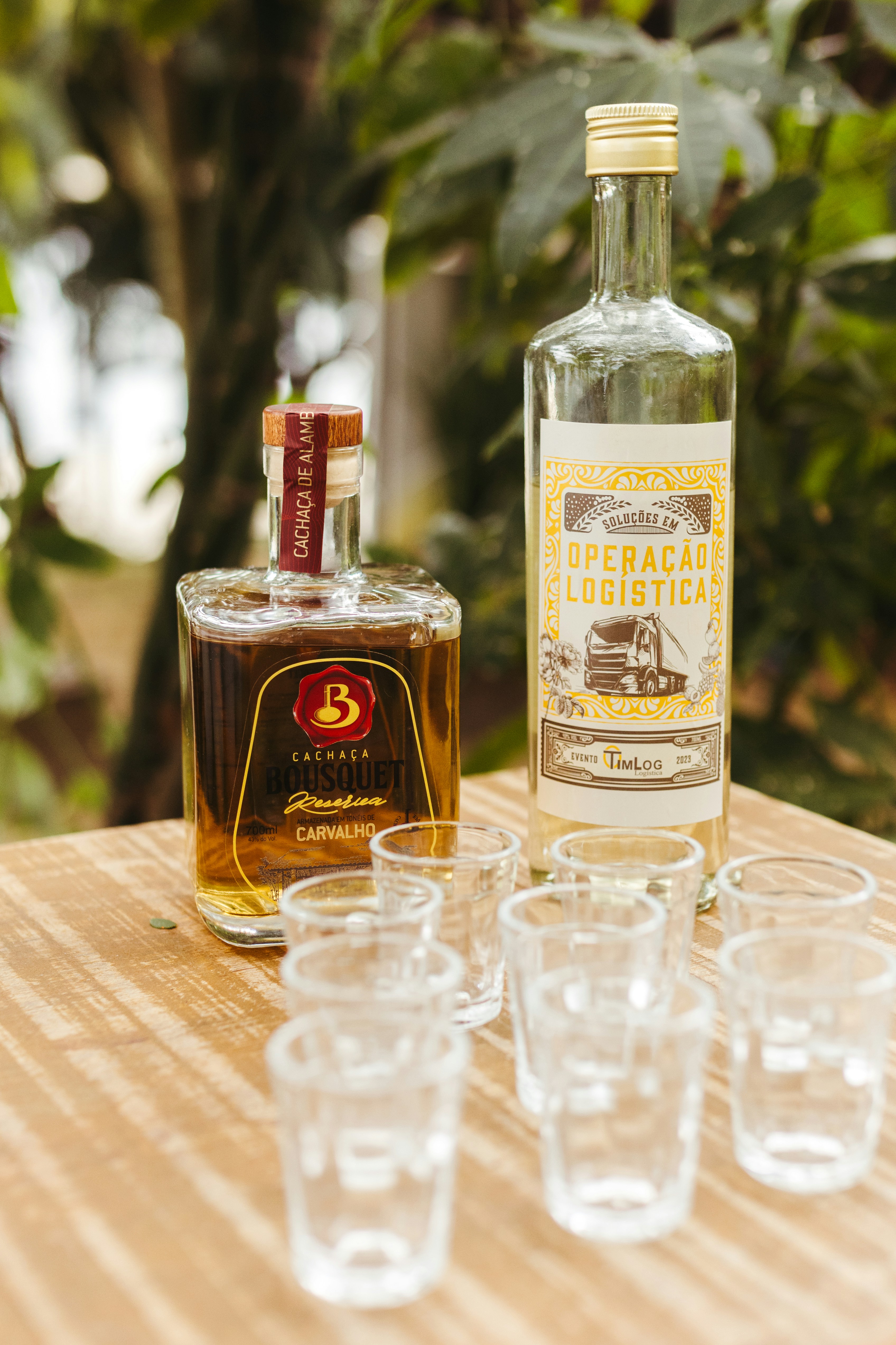 Dos botellas de cachaza y siete chupitos sobre una mesa.