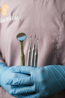 A person in blue gloves holding a set of dental instruments