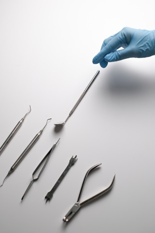 A hand in a blue glove is pointing at a set of surgical instruments