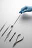 A hand in a blue glove is pointing at a set of surgical instruments
