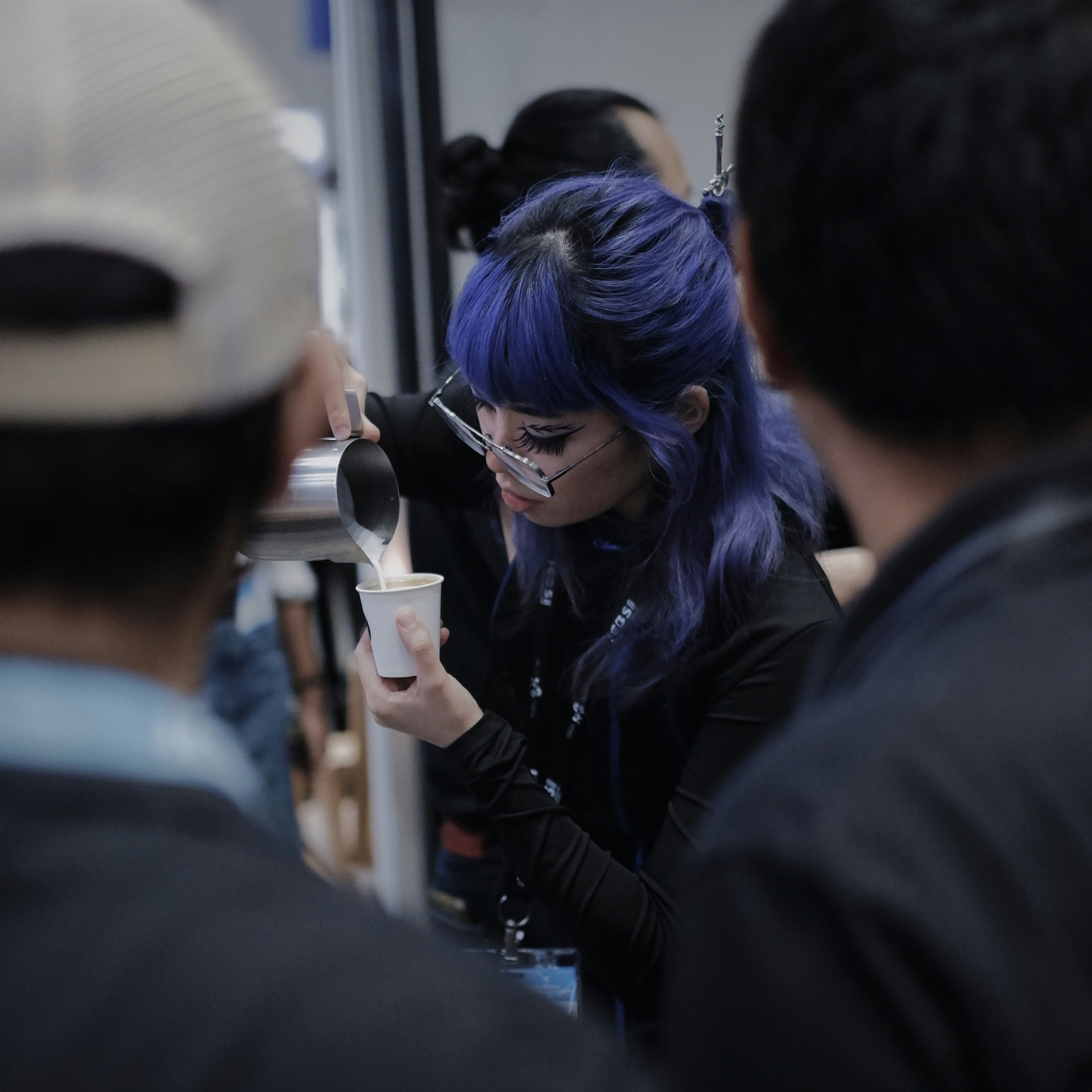 Une femme aux cheveux bleus buvant dans une tasse