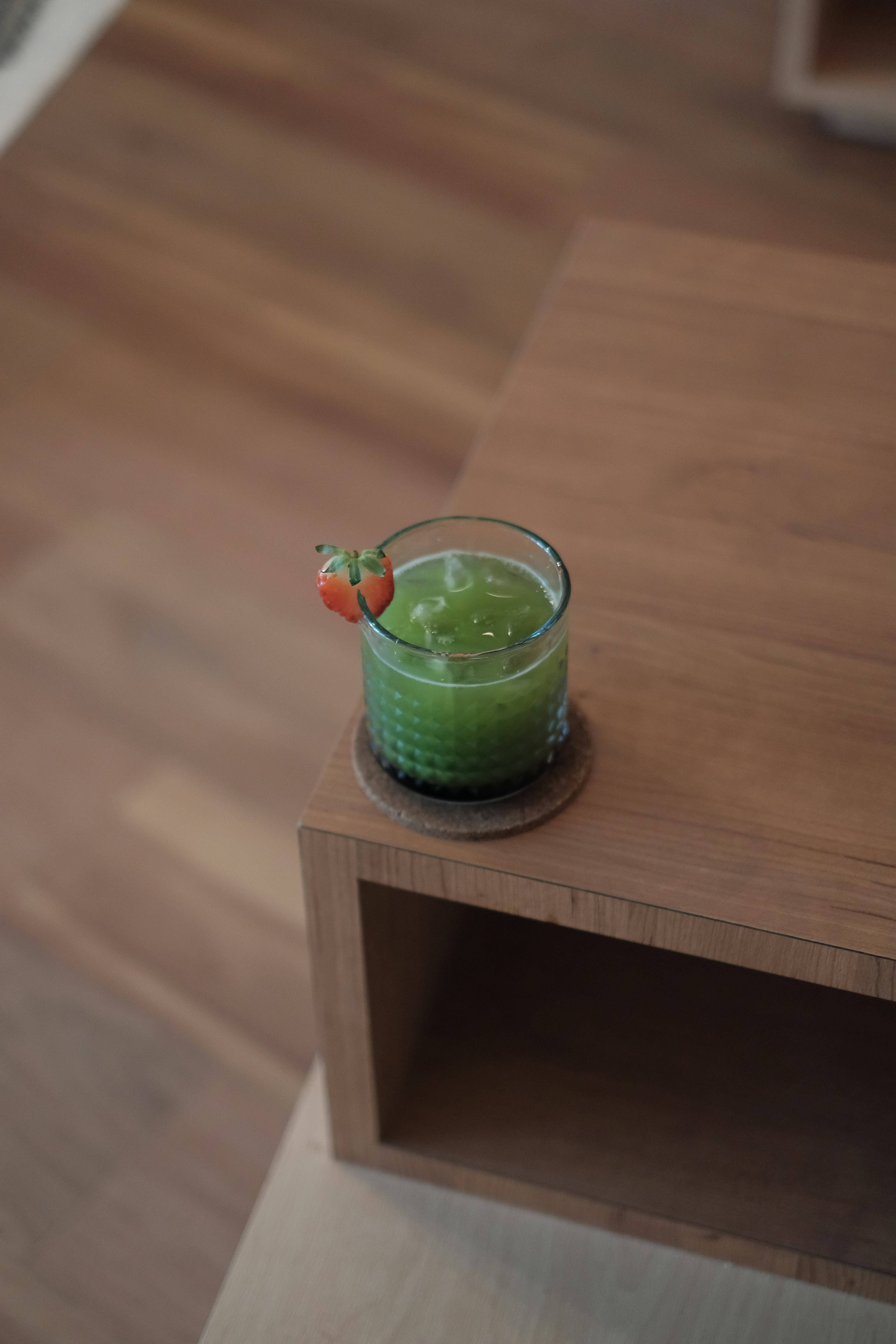 Un verre de liquide vert sur une table en bois