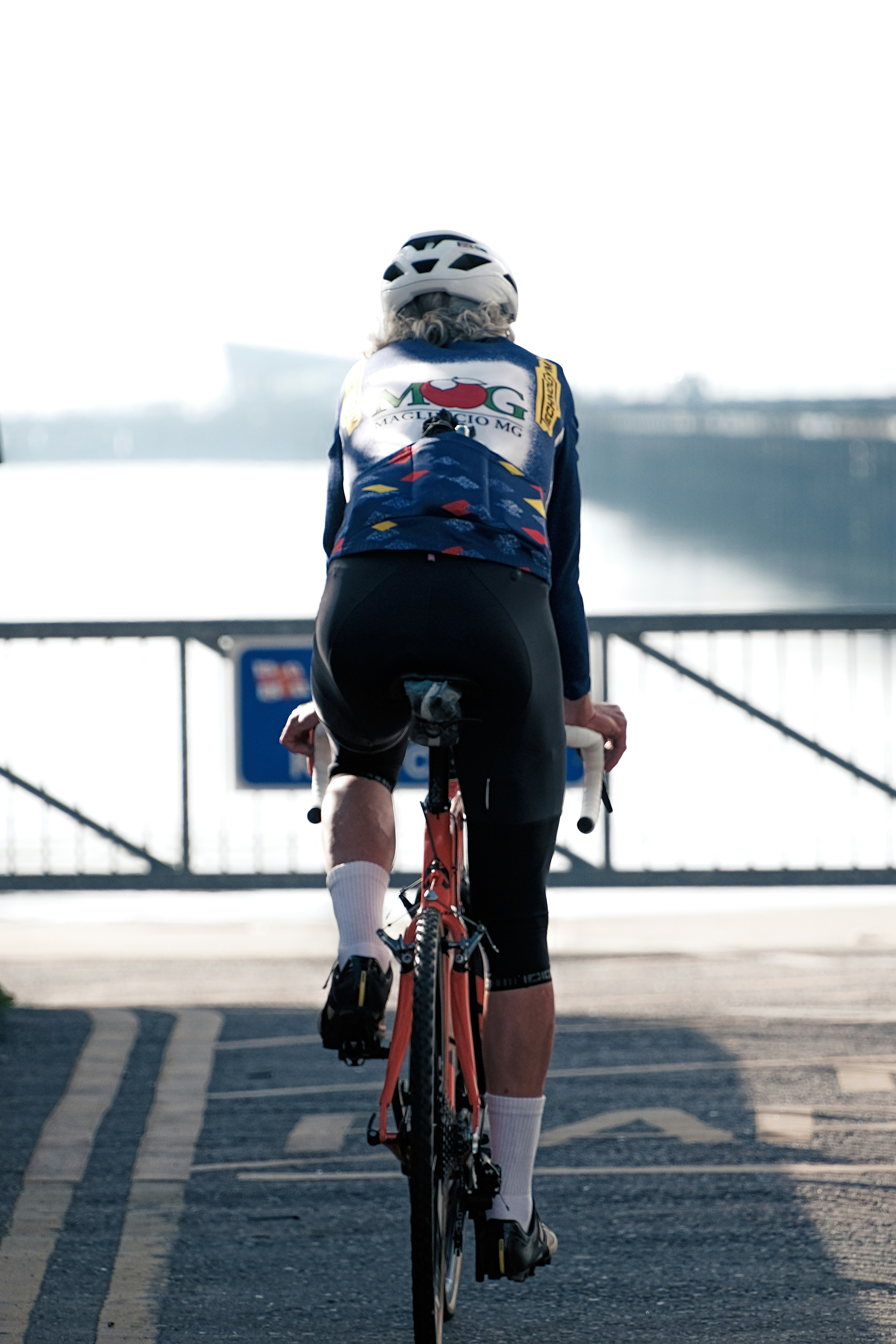 A man riding a bike down a street next to a bridge
