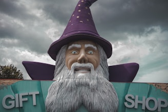 A statue of a wizard holding a sign that says gift shop