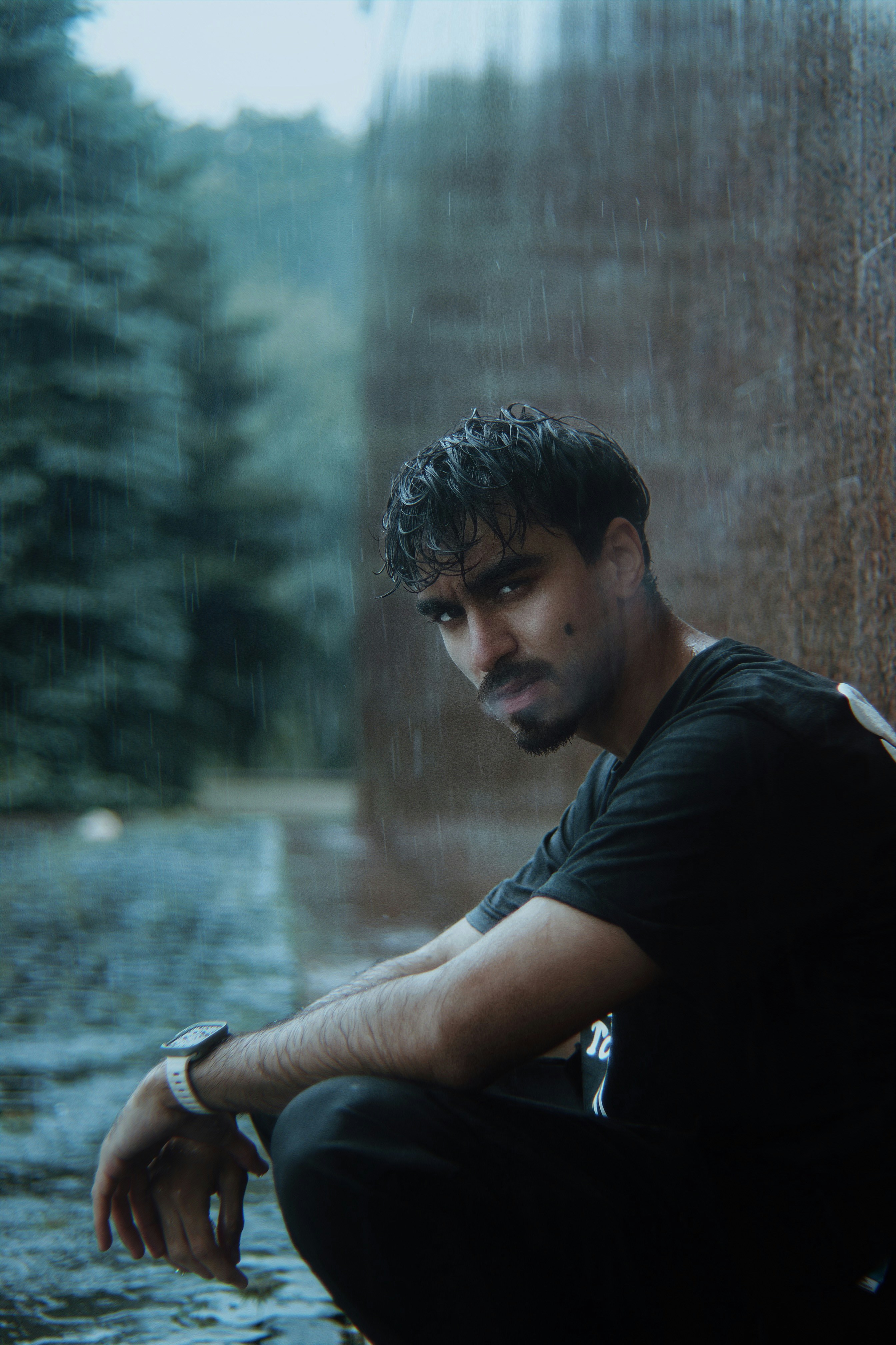 Un uomo seduto a terra sotto la pioggia