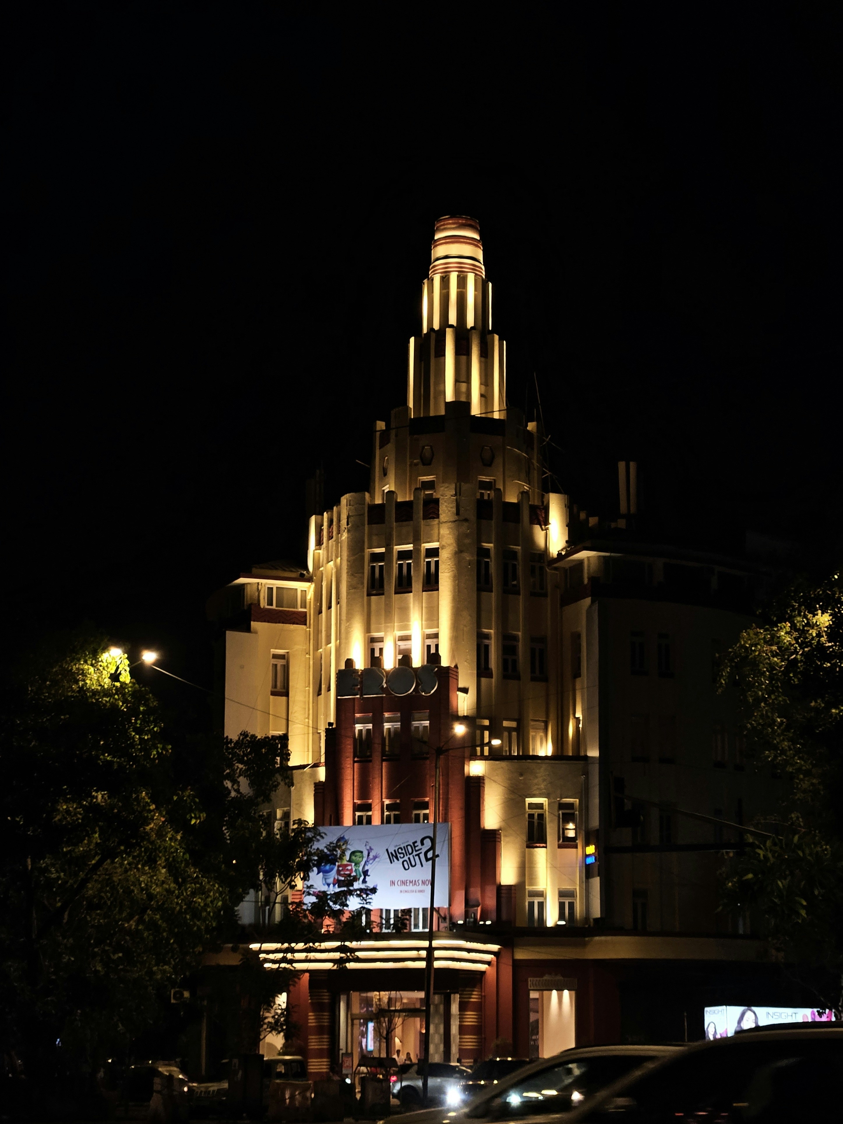 Ein großes Gebäude, das nachts beleuchtet ist und vor dem Autos parken