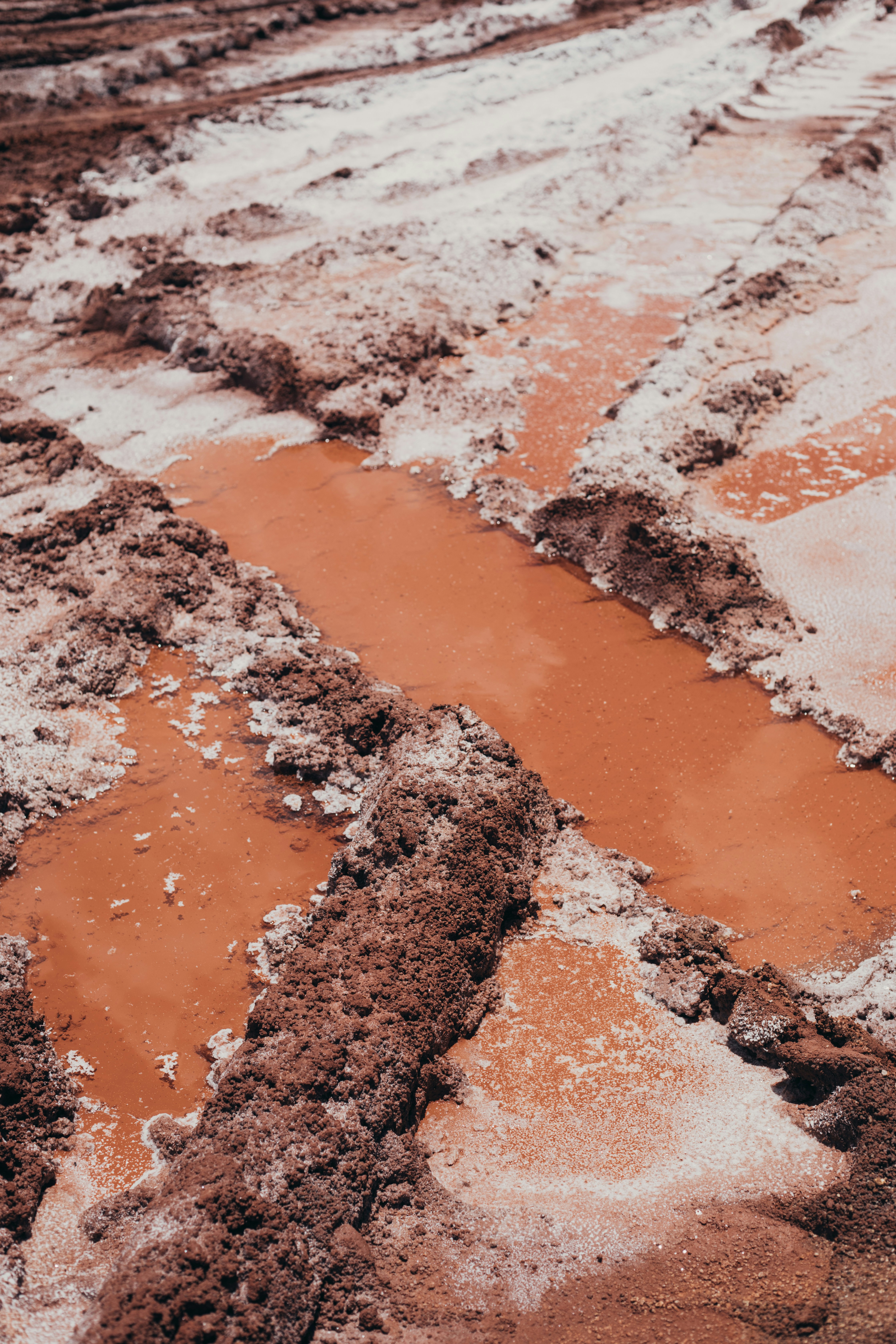 A muddy road with puddles of water on it