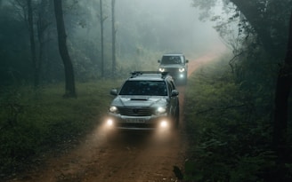 A couple of cars driving down a dirt road