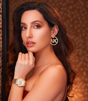 A woman in a red dress leaning against a brick wall