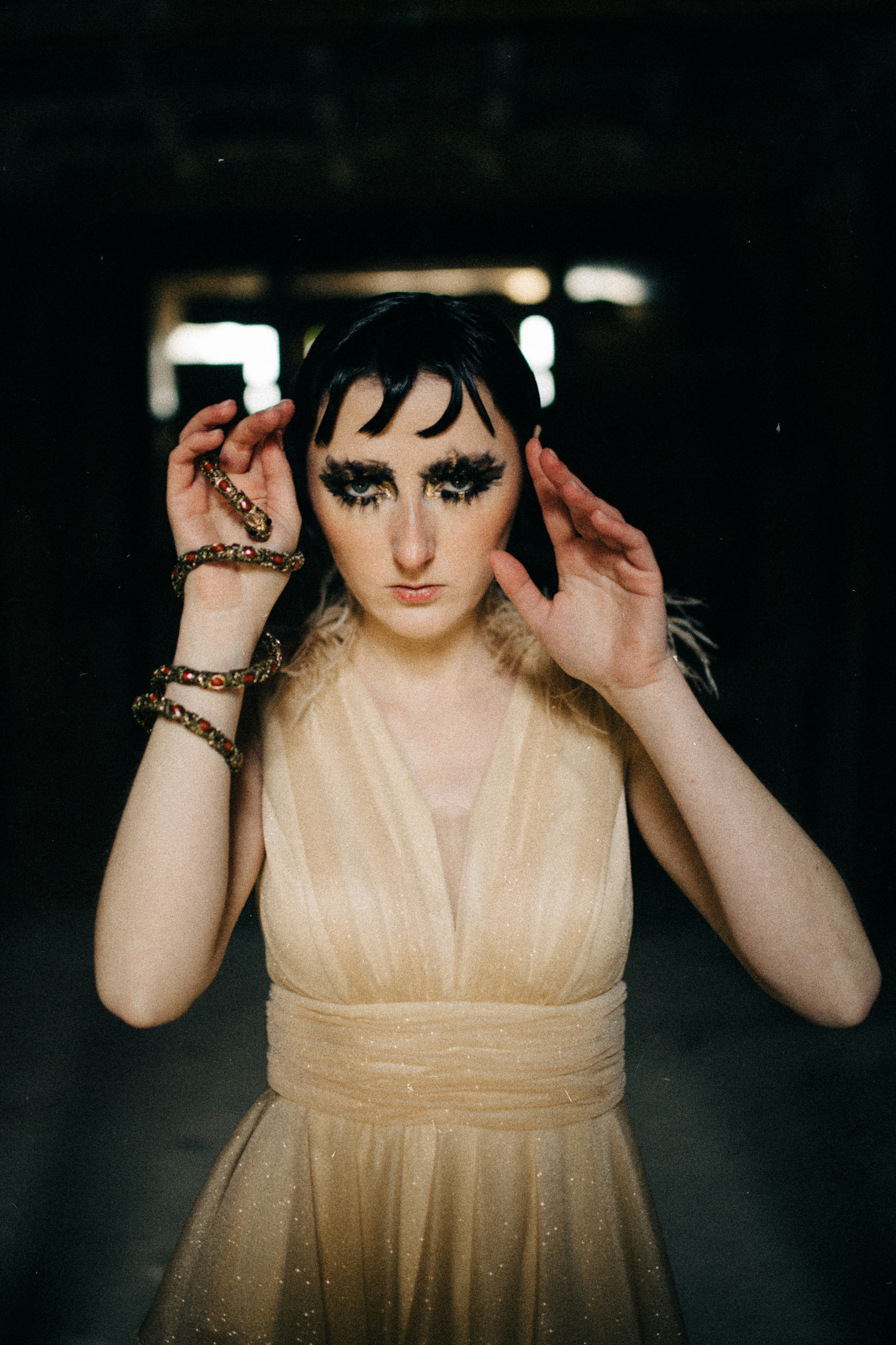 A woman in a dress holding her hands up to her head