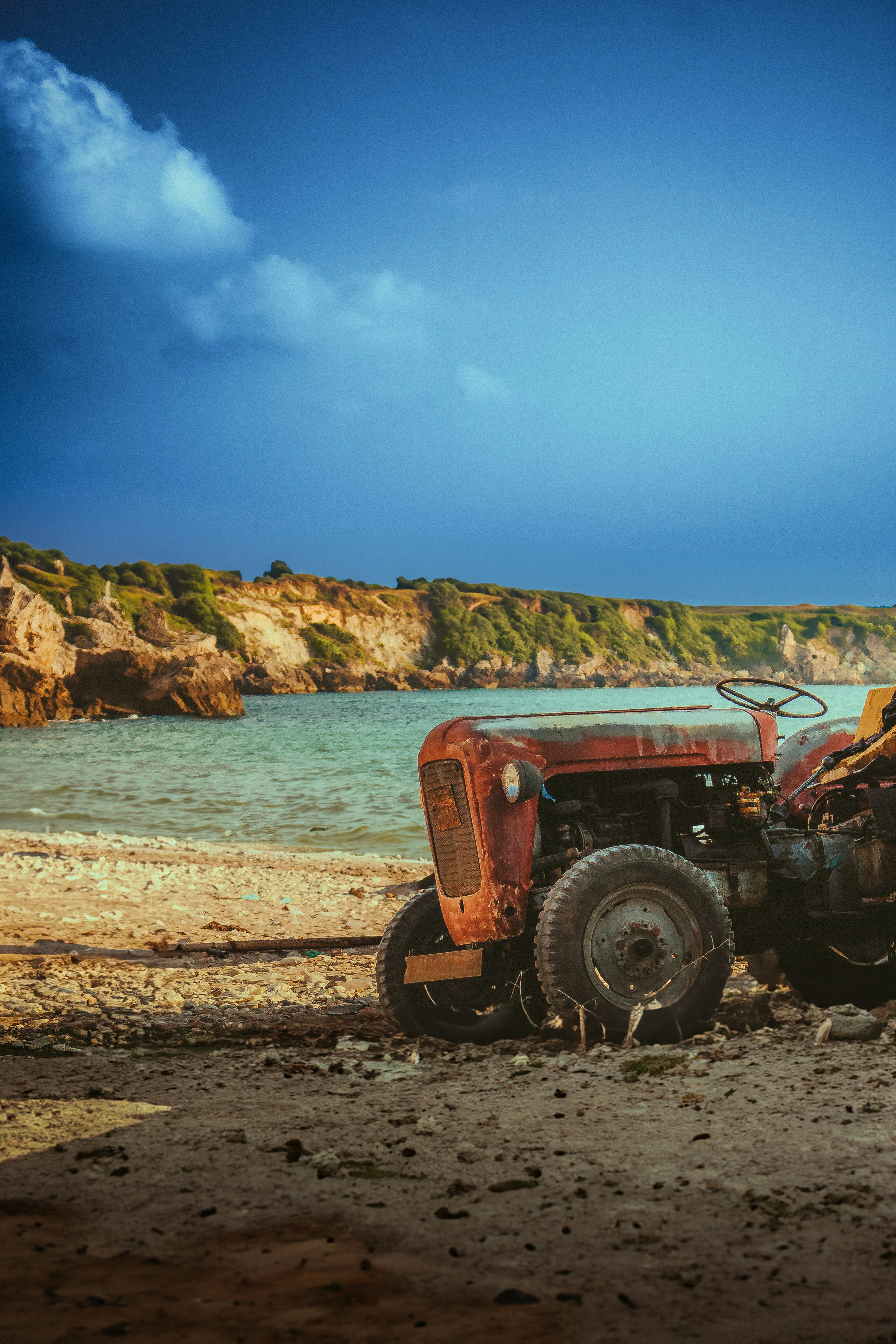 A tractor parked on a beach next to a body of water