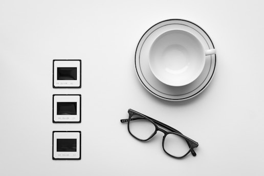 A cup of coffee, glasses, and a pair of eyeglasses on a