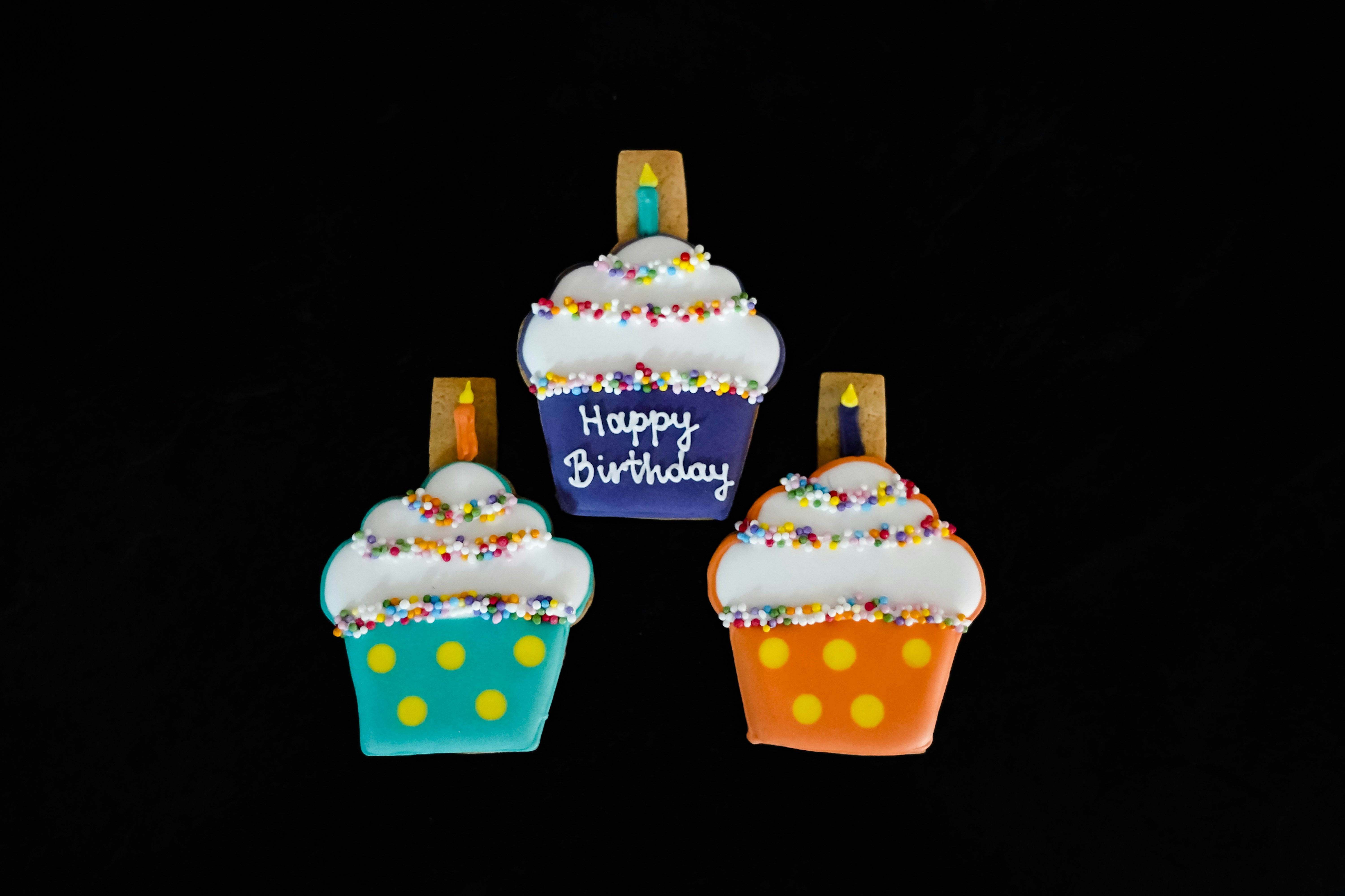 Drei dekorierte Cupcakes auf schwarzem Hintergrund