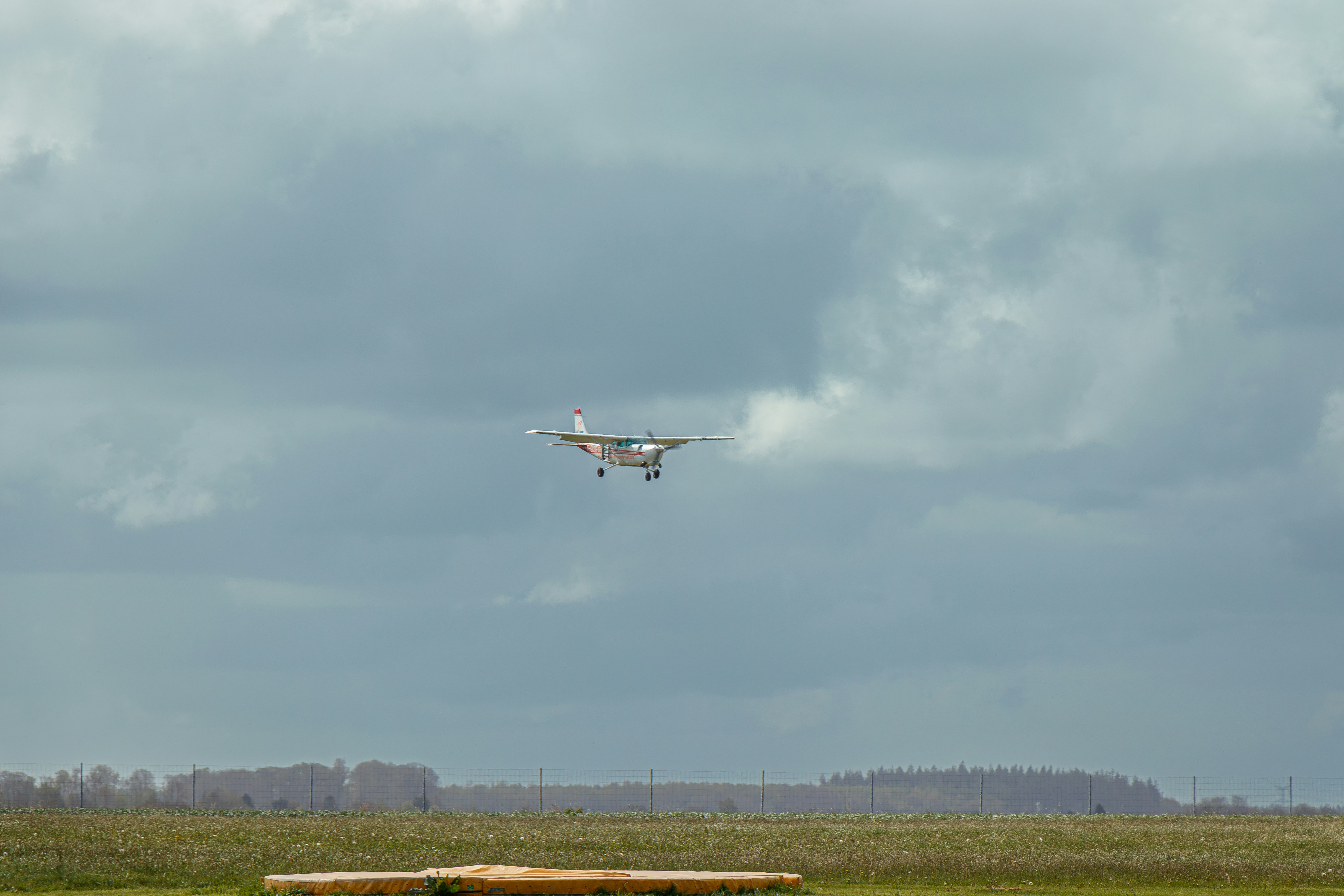 Un avión volando sobre un campo con un banco en primer plano