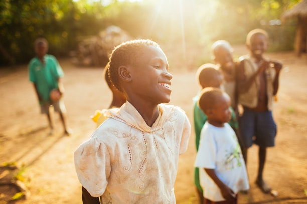 A group of young children standing on top of a dirt field