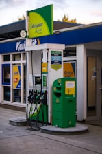 A green and white gas station with gas pumps