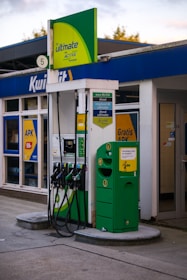 A green and white gas station with gas pumps