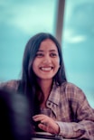 A smiling woman sitting at a table with a laptop