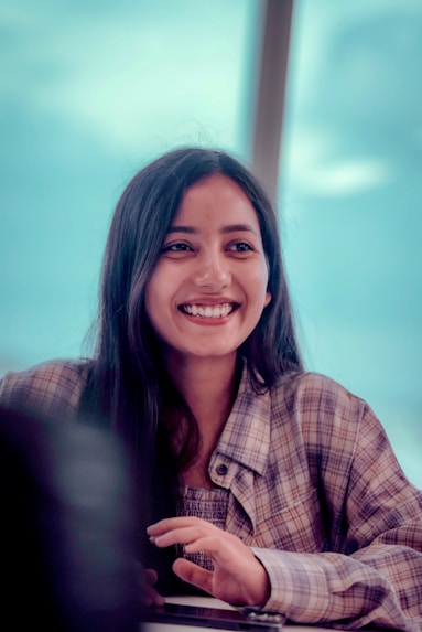 A smiling woman sitting at a table with a laptop