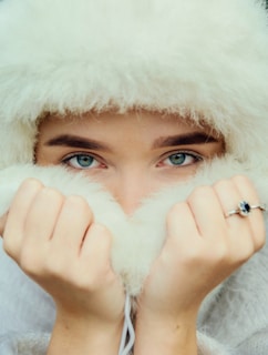 A woman wearing a white fur hat covering her eyes