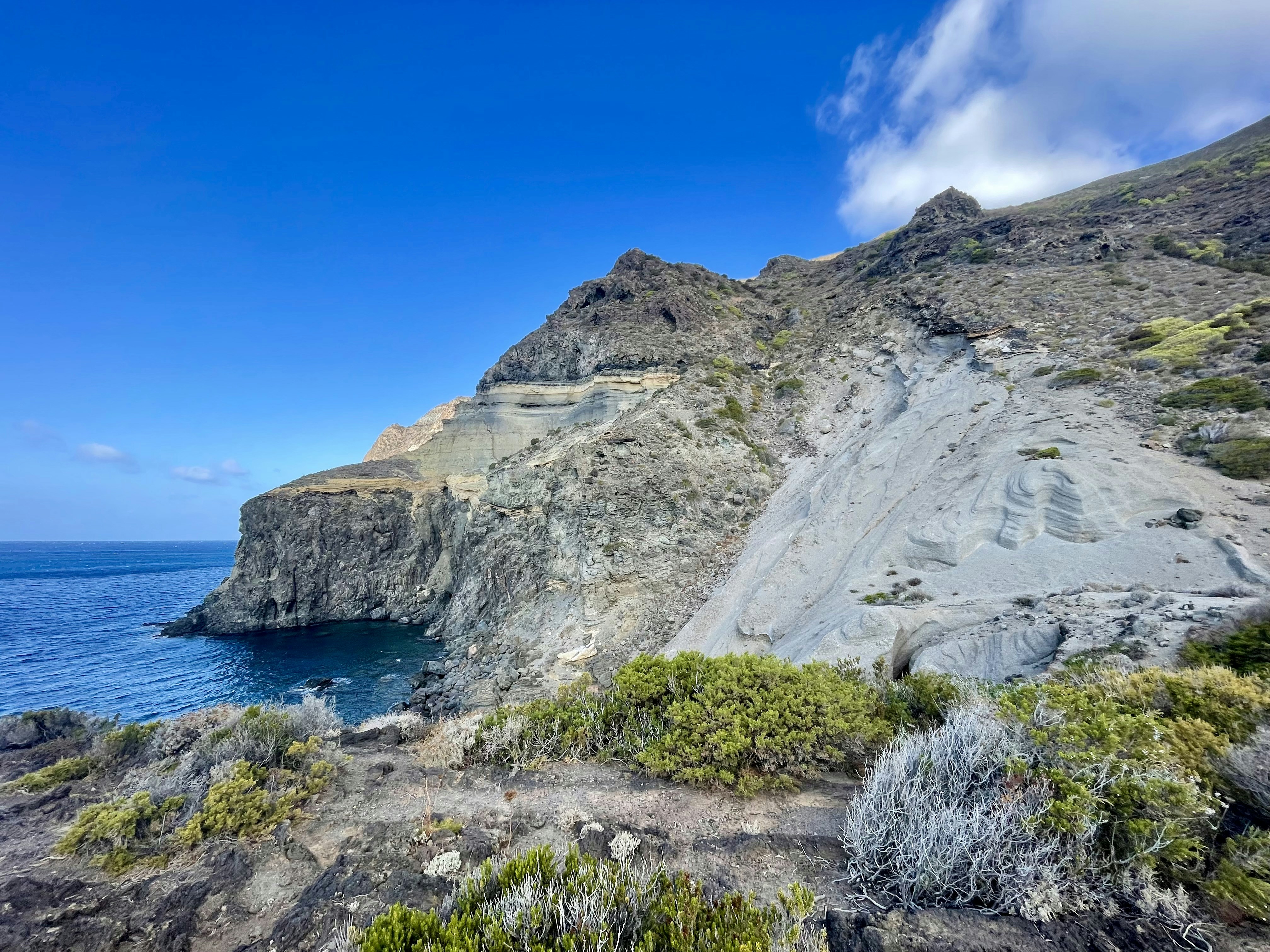 A rocky cliff overlooks the ocean on a sunny day